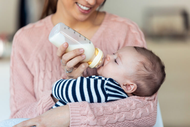 moeder geeft fles aan baby